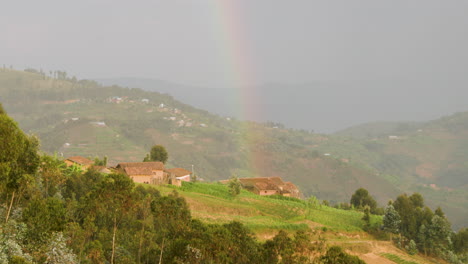 long shot of hill side home in rwanda with rainbow sitting on top of the home