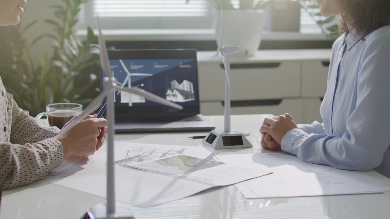 Close Up of Two Female Colleagues Discussing Wind Turbine Model in Office