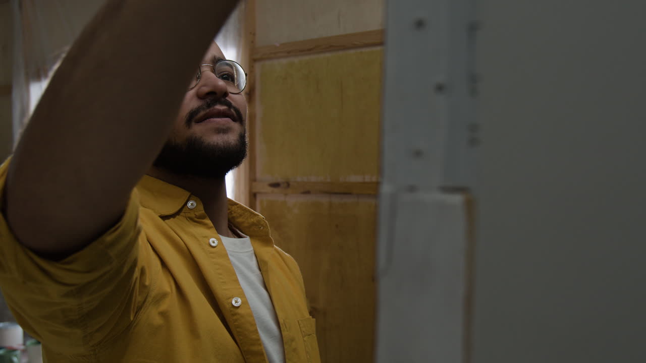 A man wearing glasses and a yellow shirt indoors