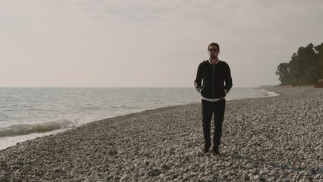 uomo che cammina su una spiaggia di ciottoli