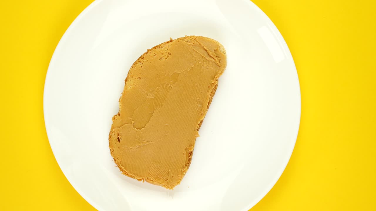 Peanut butter, jam sandwich rotating, turning round on yellow background.