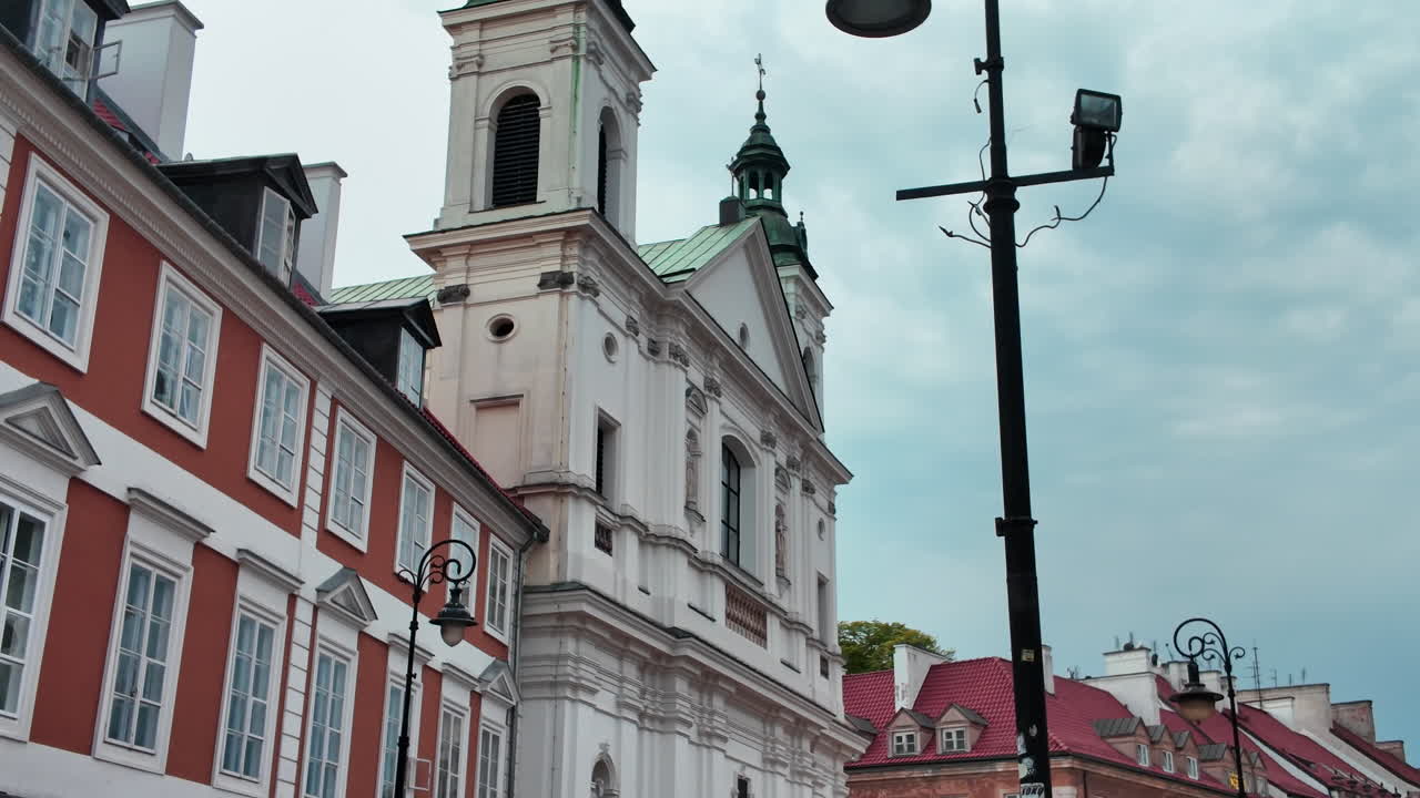 Historic white church facade in Warsaw with baroque towers under cloudy sky