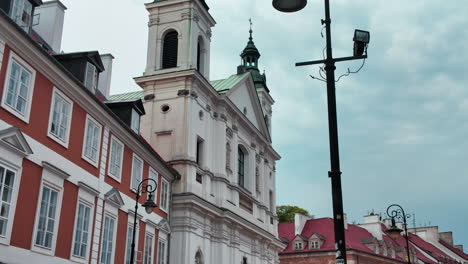 historic white church facade in warsaw with baroque towers under cloudy sky
