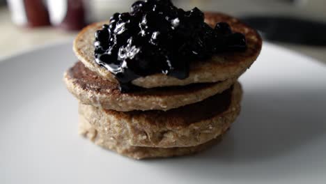 garnishing four stacked pancakes with blueberry sauce, slow motion