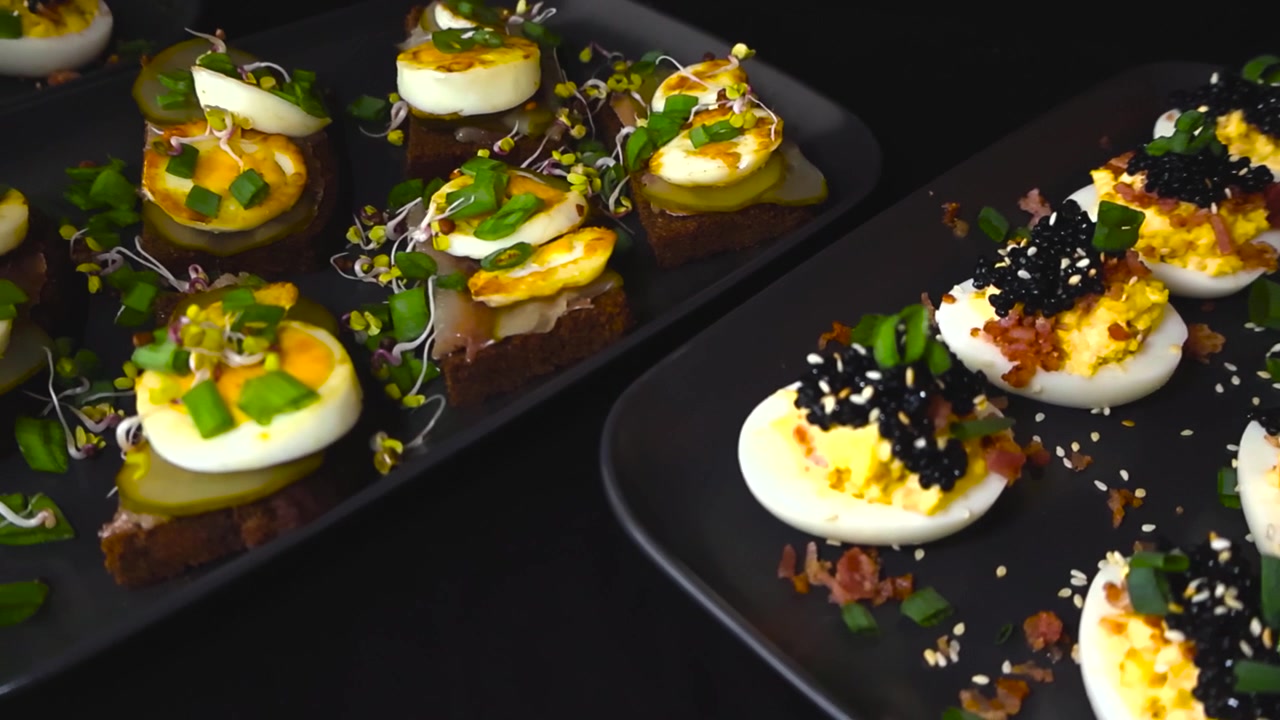Délicieux canapés et œufs mimosa garnis de caviar noir, de bacon et de ciboulette, tournant sur des assiettes noires, représentant un assortiment luxueux et appétissant de plats de fête faits maison