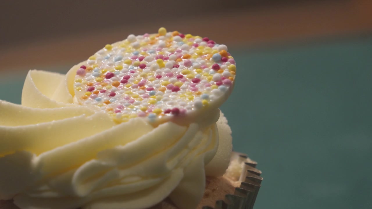 Slow Pan to Indulgent White Chocolate Cupcake with Buttercream Frosting. Close Up Snack Dessert Food Photography.