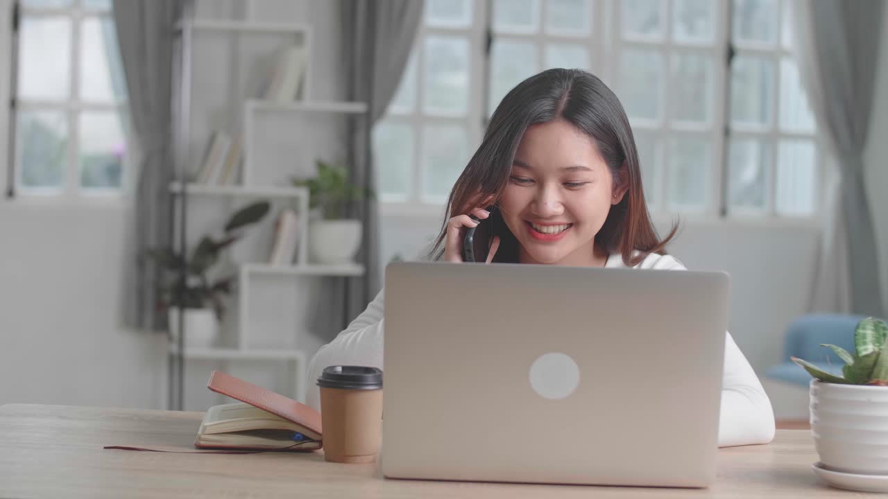 Happy Girl Talking On Phone During Work With Laptop Computer At Home, Video In 4K