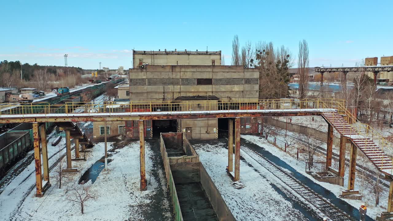 A row with containers on the railway line stand at the entrance to the tunnel on the background other rows in the terminal station in the winter season. Aerial view.