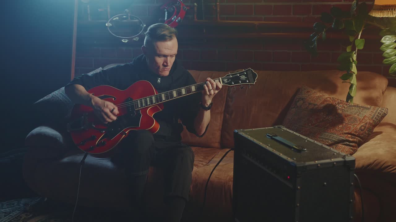 Homme jouant de la guitare jazz à la maison
