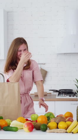 young woman in modern kitchen. portrait of a smiling happy girl throwing apples in kitchen. vertical video
