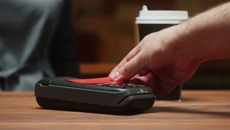 paying with credit card in caffe close-up. cashless shopping in restaurant. touch-free and contactless payment concept. nfc technology and bank terminal. buying coffee.