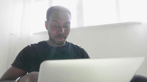 man looking surprised at laptop near window