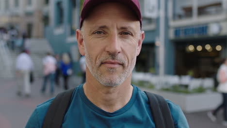 close up portrait of mature attractive caucasian tourist man wearing hat looking at camera pensive city background