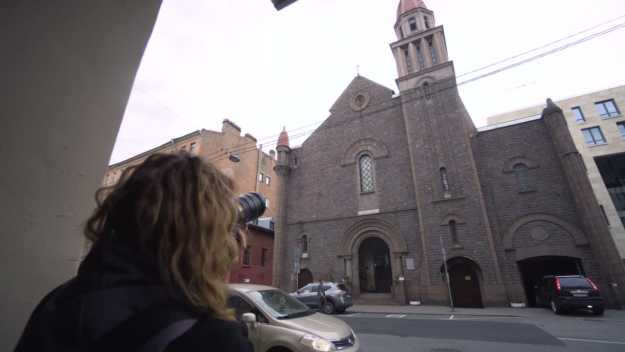 mujer tomando una foto de una iglesia en la ciudad