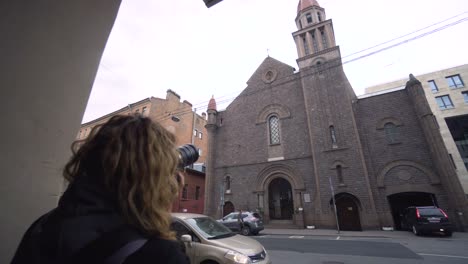 woman taking a photo of a church in the city