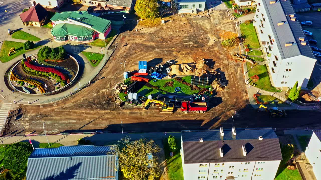 Chantier de construction urbain avec machinerie lourde, développement d’une nouvelle zone résidentielle près d’un rond-point moderne