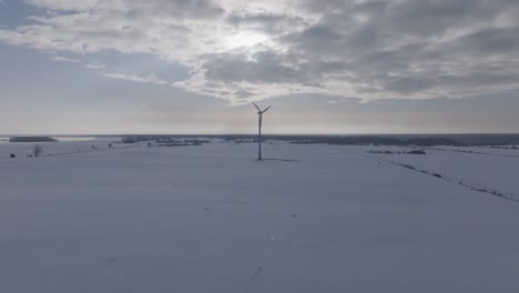 drone circles a solitary wind turbine amidst a snow-blanketed baltic landscape under a brooding sky