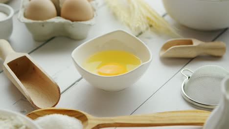 utensils and ingredient around bowl with yolk