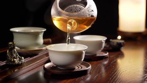 pouring hot golden tea into a cup during a traditional ceremony.