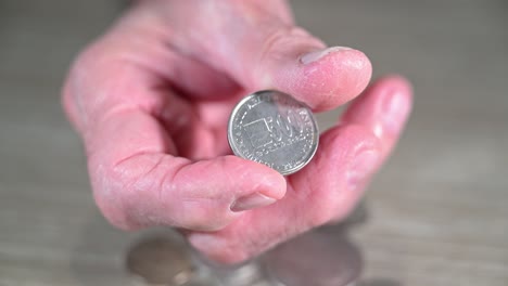 mano venezolana anciana pone una moneda de bolívar venezolano en su mano y la tuerce
