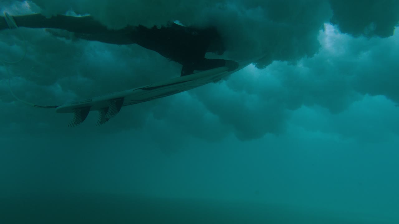 A wave breaks as a surfer duck dives.