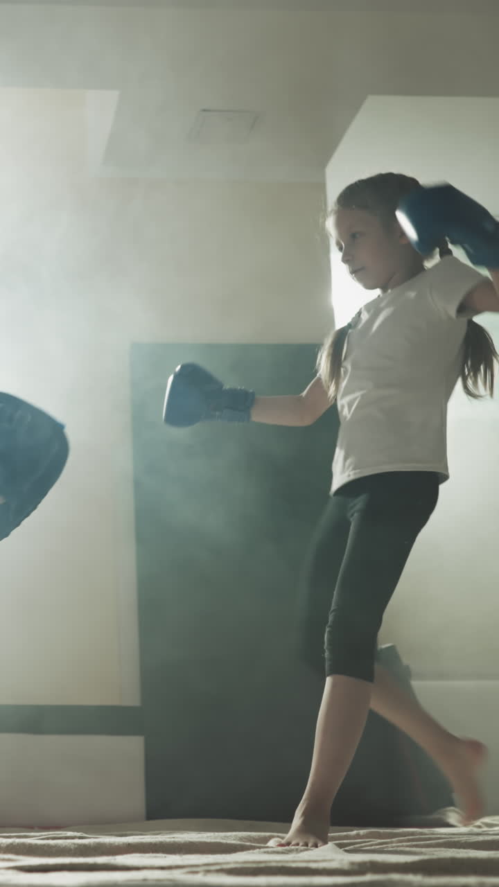 el niño patea la almohadilla con el apoyo del entrenador en el gimnasio de combate. el entrenador de kickboxing enseña a la niña descalza el ataque con la pierna en la escuela de deportes en cámara lenta. lección de autodefensa