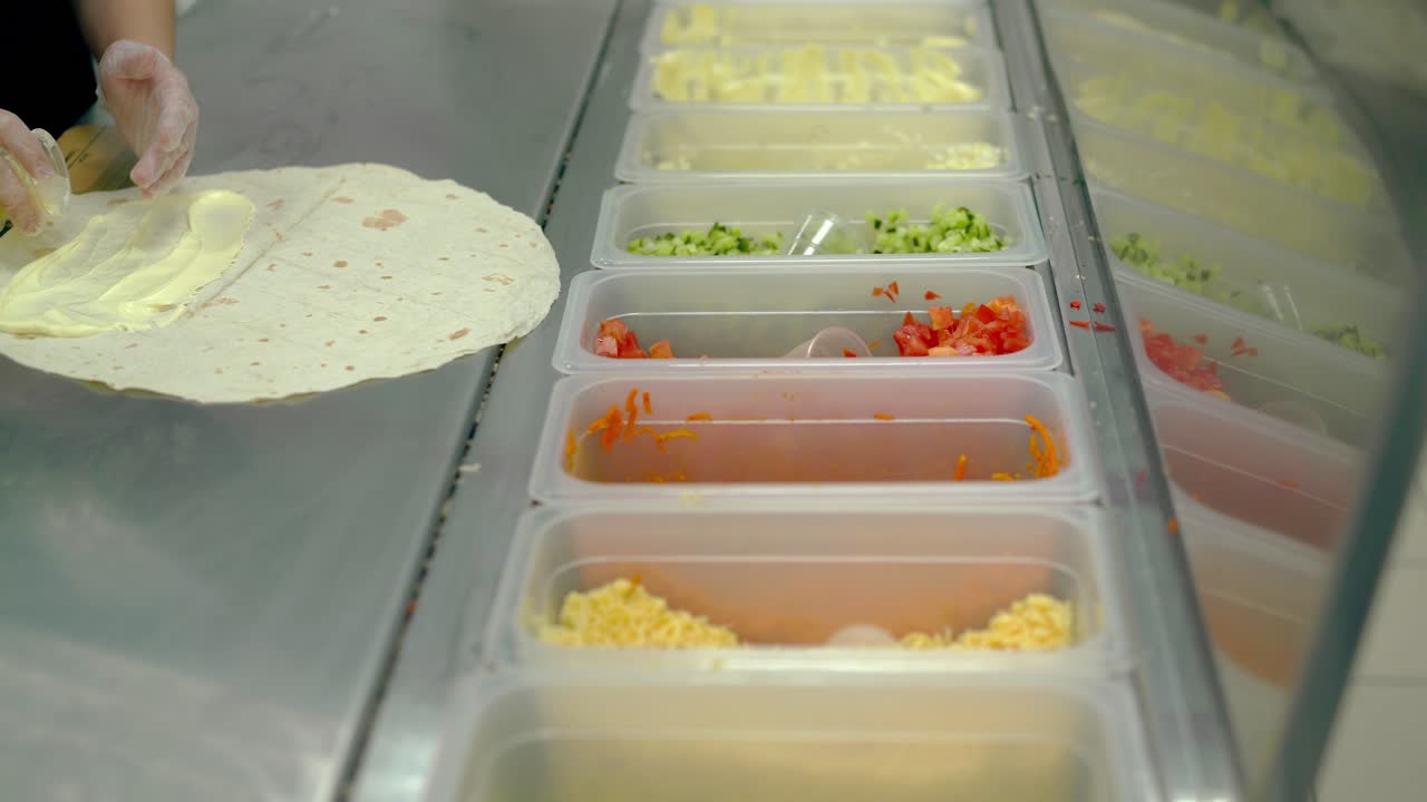 el cocinero prepara shawarma o wok pone verduras en un pastel plano con mayonesa