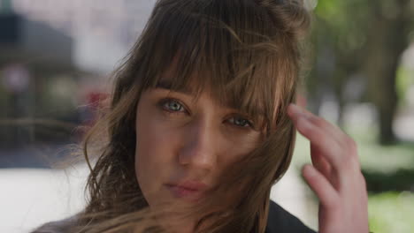 Primer-Plano-Retrato-De-Una-Hermosa-Mujer-Joven-Mirando-La-Cámara-Corriendo-Con-La-Mano-A-Través-Del-Cabello-Calmada-Mujer-Caucásica-Mirando-Contemplativa-En-El-Fondo-Urbano-De-La-Ciudad-En-Cámara-Lenta