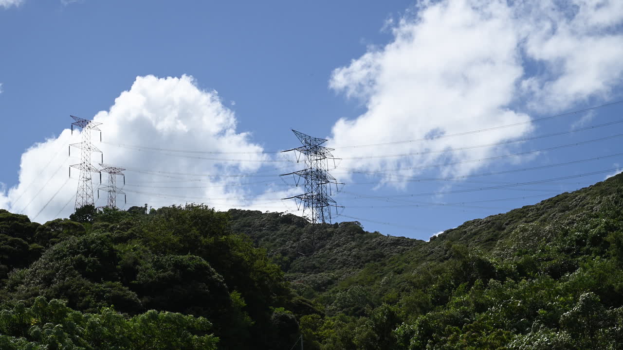 Power Lines and Transmission Towers on Green Hillside with Moving Clouds