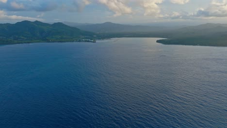 Aerial-forward-over-calm-and-blue-waters-of-Maimon-Bay-at-sunset,-Puerto-Plata-in-Dominican-Republic