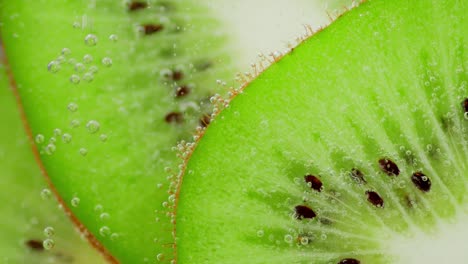 slices of ripe kiwi under water with air bubbles. macro background.