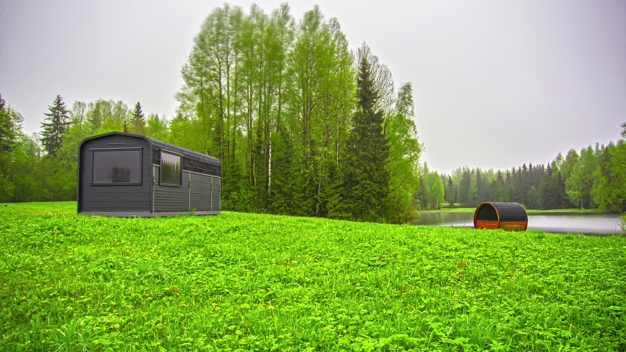 안개 낀 일출 동안 녹지 풍경에 써모우드 배럴 사우나가 있는 열 목재 오두막