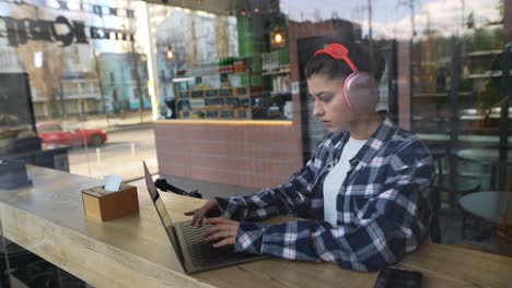mujer joven trabajando en una computadora portátil en un café