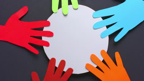 Close up of hands touching circle made of colourful paper on gray background with copy space