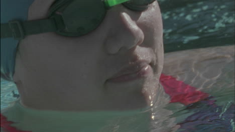 a female swimmer turns around in the water and smiles