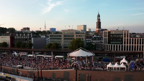 hamburg harbour at hamburg cruise days festival with crowd of people and michel in the background at golden hour