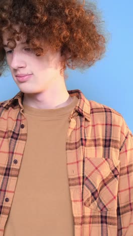 cute young happy student on blue background looking at phone cute young happy student on blue background looking at phone curly redhaired guy is crazy happy internet search technologies