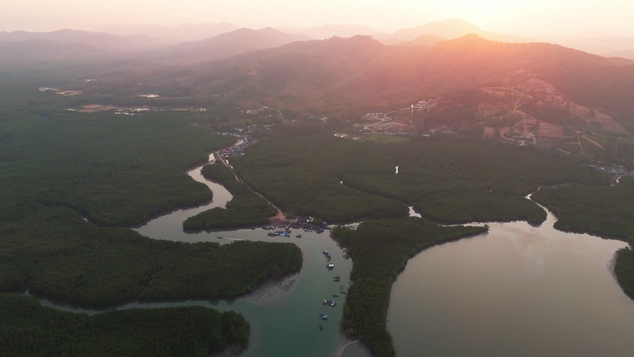Sunset over Phang Nga Bay, Thailand, golden hues reflecting on winding rivers and limestone mountains, aerial establishing dolly