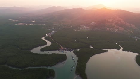 sunset over phang nga bay, thailand, golden hues reflecting on winding rivers and limestone mountains, aerial establishing dolly