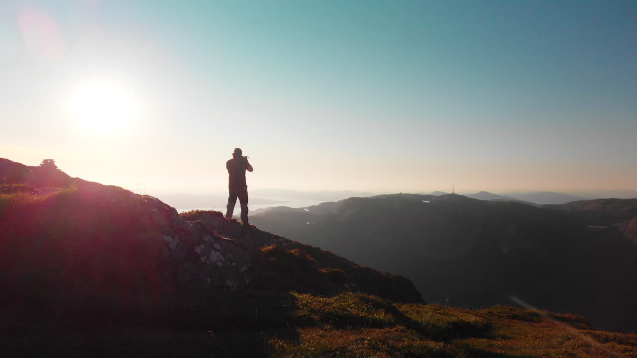 hombre caminando al final de un acantilado, fotografiando el hermoso paisaje - antena 4k