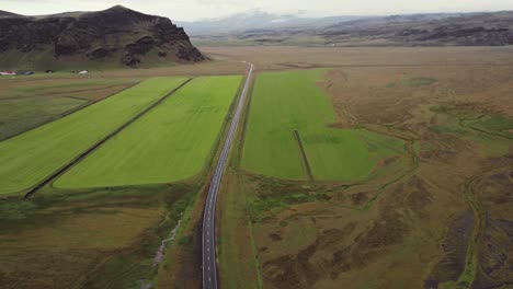 Aerial-car-driving-on-ring-road-Iceland,-nature-grassy-moss-mountain-landscape