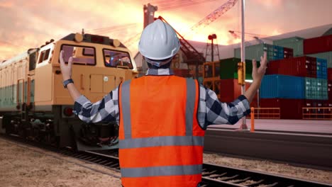 back view of a male engineer with safety helmet spreading arms while standing with freight cargo train at port