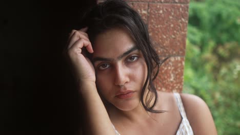 Close-up-portrait-of-a-woman-with-a-contemplative-expression,-resting-her-head-on-her-hand-while-gazing-directly-into-the-camera