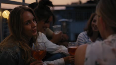 28 chicas caucásicas hablando juntas en una fiesta nocturna en la azotea.