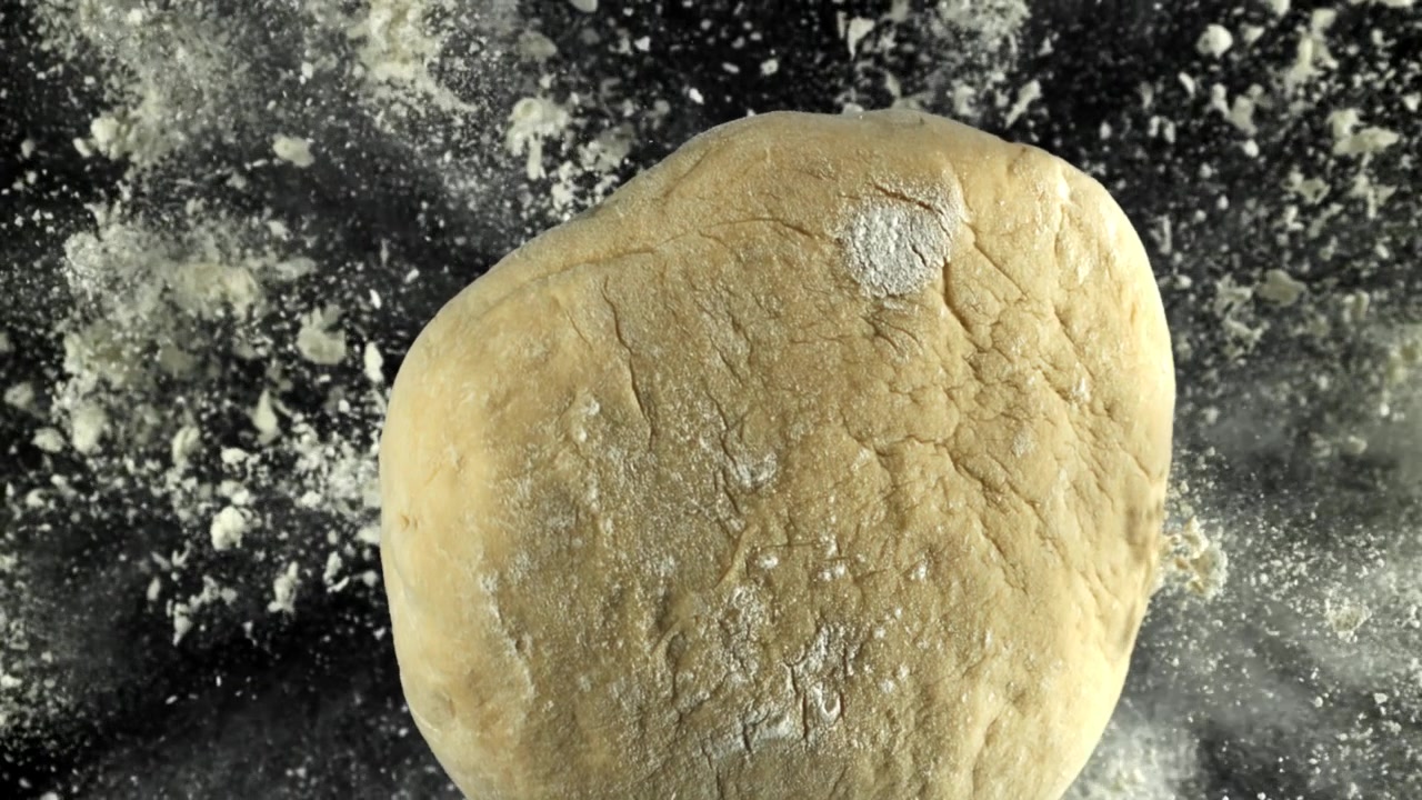 Flour Falling on Fresh Dough Ball on Dark Surface