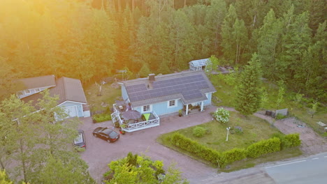 aerial view circling a detached house with pv cells on the roof, summer sunset