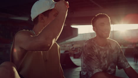 Stylish-hipsters-relaxing-skatepark-at-sun-rays.-Friends-talking-together.