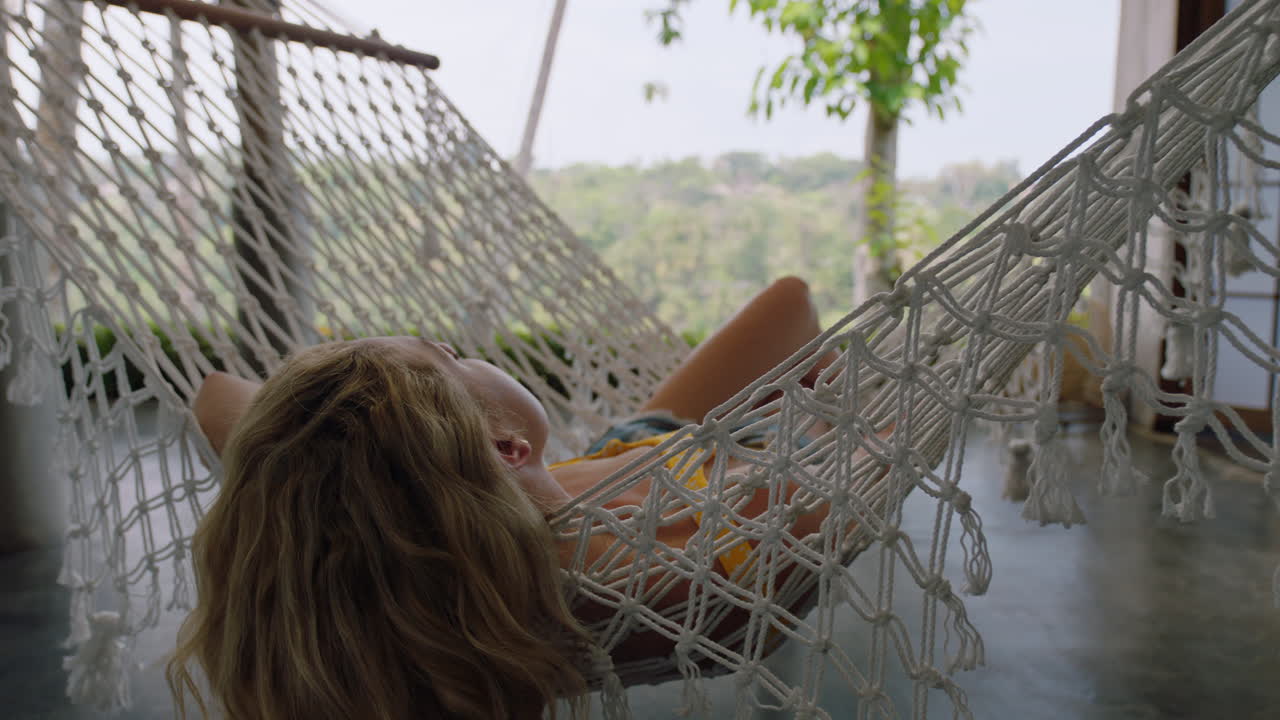 mujer joven en hamaca balanceándose pacíficamente en un perezoso día de verano disfrutando del estilo de vida de vacaciones en el complejo vacacional