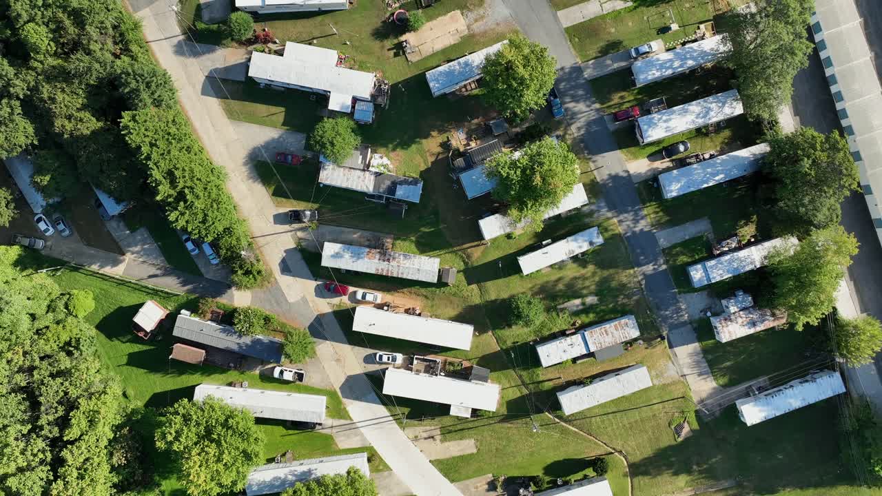 Mobile trailer homes in American suburbia during sunny day. Aerial top down. Dangerous low income housing area of American metropolis. Summertime in USA