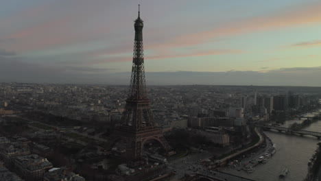 Aerial-footage-of-one-of-Paris-dominants-at-dusk.-Eiffel-Tower-on-Seine-riverbank-and-evening-city-in-background.-Paris,-France